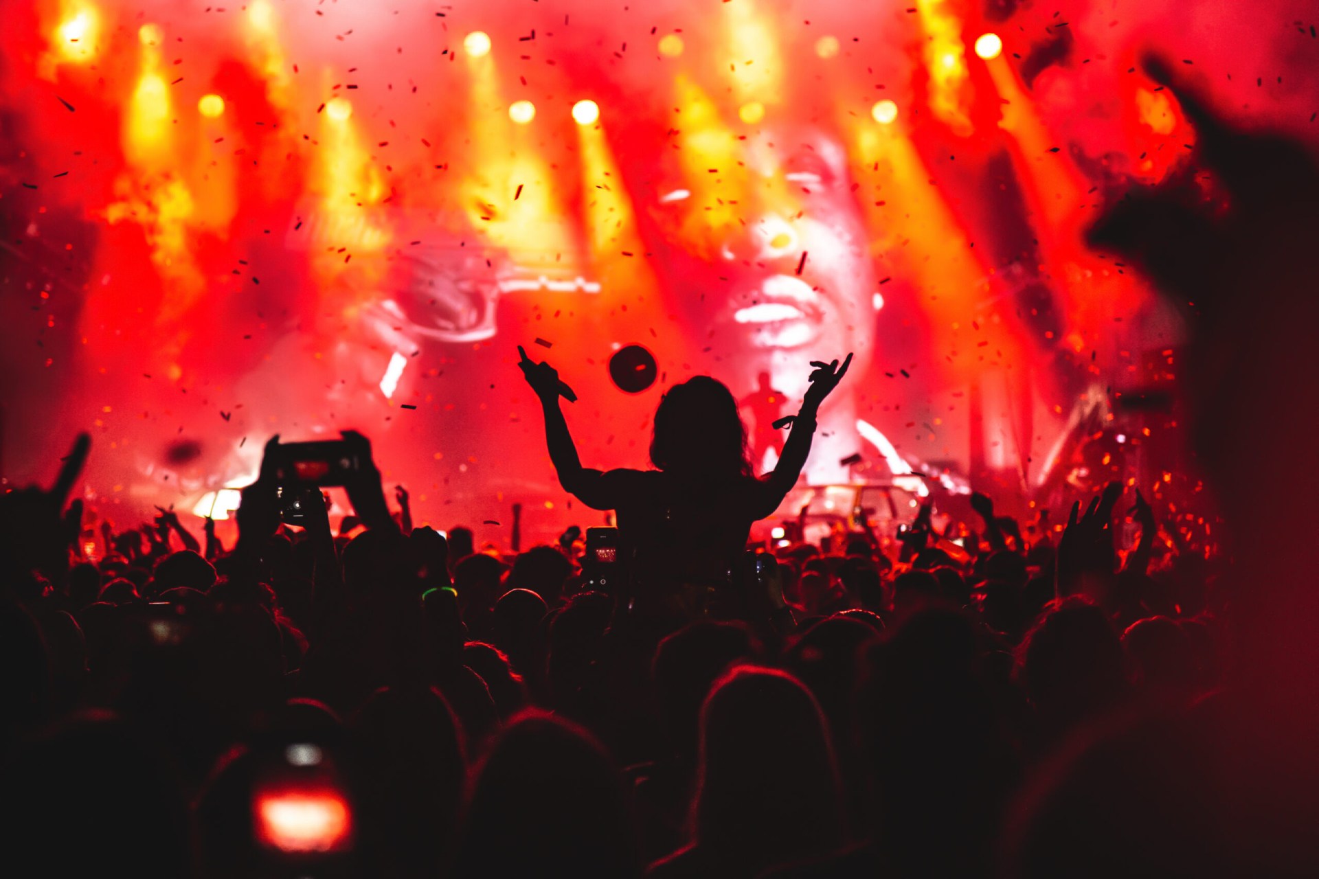 Girl on shoulders in the crowd at a music festival.